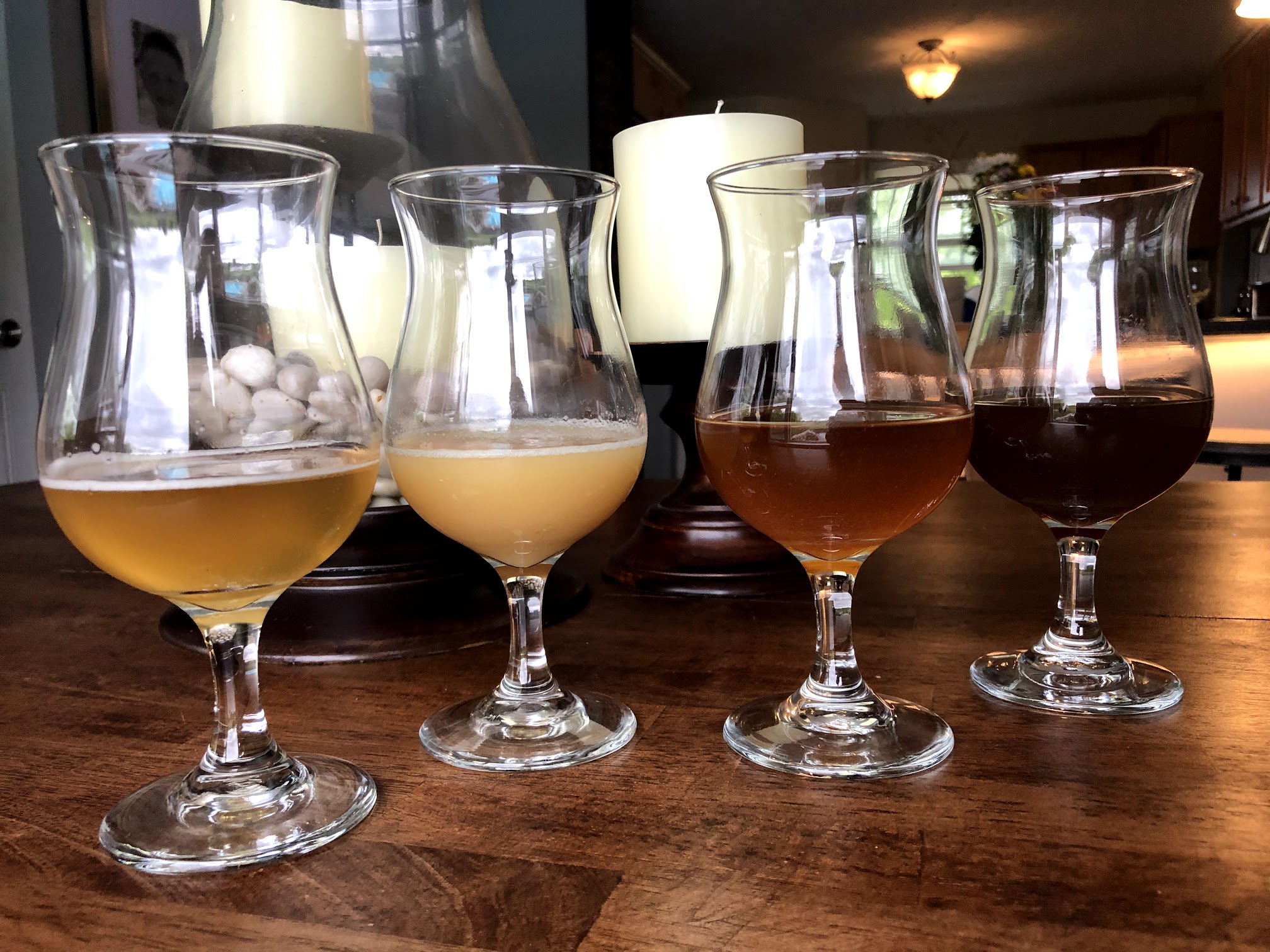 A flight of four homebrewed beers, from a pale blonde to a dark amber